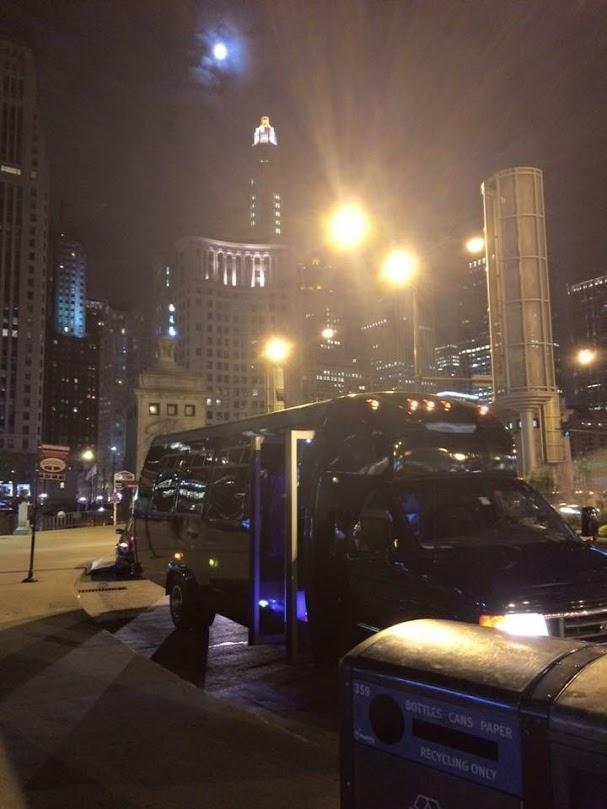 Local party bus rental service in Chicago, Party bus against the Chicago skyline at night, from Stop & Go Limo Airport Shuttle Service.